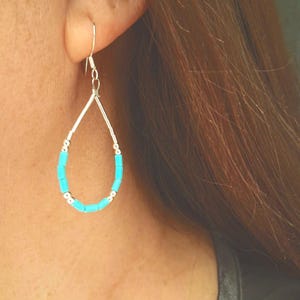 May include: A teardrop-shaped earring featuring a silver-toned wire frame accented with small, cylindrical turquoise-colored beads and tiny silver-toned spacer beads. The earring hangs from a simple silver-toned hook wire for pierced ears.