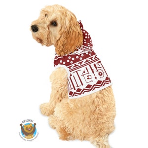 May include: A brown and white dog wearing a red hooded sweater with a white geometric pattern and tools printed on it. The sweater has a white hood with a white drawstring.