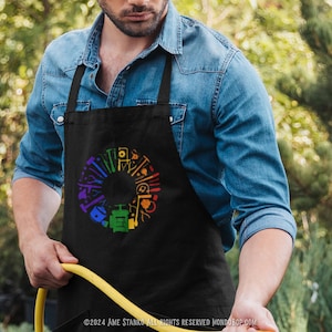 May include: A black apron with a rainbow circle design featuring various tools. The circle is made up of different colored tools, including a hammer, wrench, screwdriver, and saw.