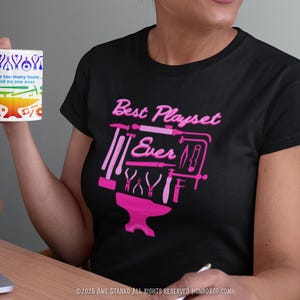 May include: A black t-shirt with a pink graphic of a blacksmith's anvil and tools. The text "Best Playset Ever" is written above the graphic. The text "I have too many tools, said no one ever." is written on a mug in the image.