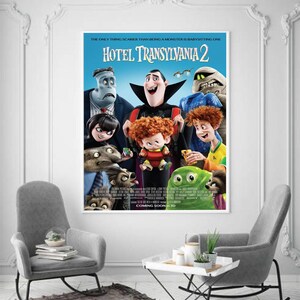 May include: A framed movie poster for "Hotel Transylvania 2" featuring cartoon characters. The poster has a blue background with the movie title and the tagline "The only thing scarier than being a monster is babysitting one."