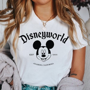 K&ouml;nnte beinhalten: Wei&szlig;es T-Shirt mit einem schwarzen Mickey Mouse-Motiv und dem Text "Disneyworld Est. 1955 Anaheim, Kalifornien".