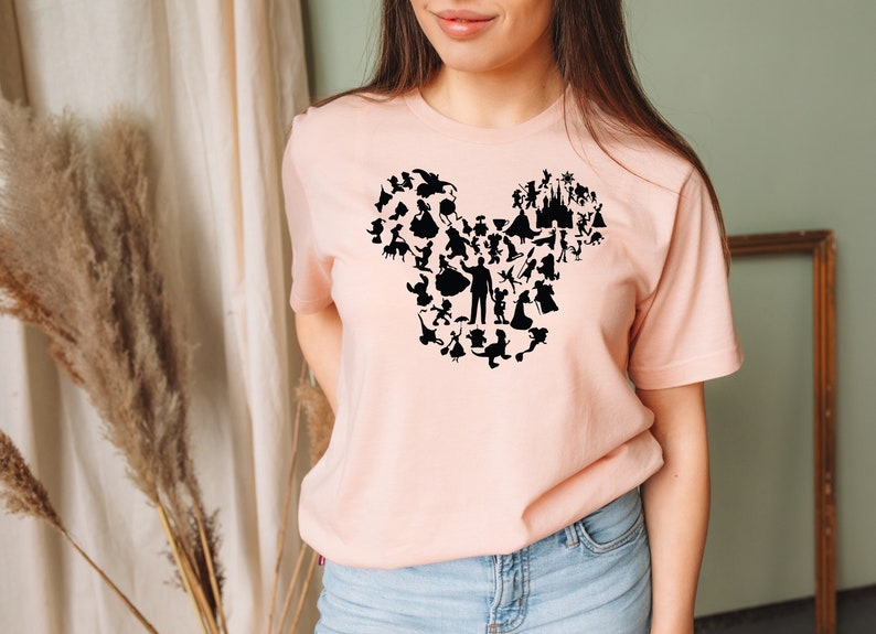 May include: A pink t-shirt featuring a black silhouette of Mickey Mouse's head formed from various Disney characters.