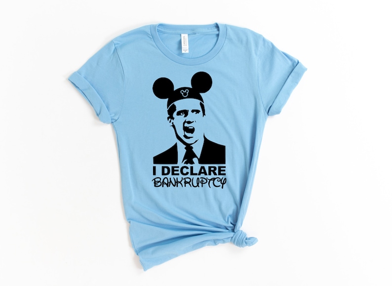 May include: A light blue t-shirt with a black silhouette of a man wearing Mickey Mouse ears. The man is shouting and the text "I DECLARE BANKRUPTCY" is below him.