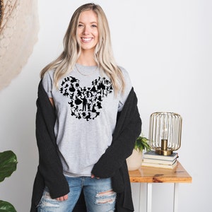 May include: A grey t-shirt featuring a black silhouette of Mickey Mouse's head formed from various Disney characters and icons.
