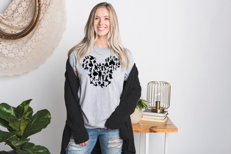 May include: A grey t-shirt featuring a black silhouette of Mickey Mouse's head formed from various Disney characters and icons.