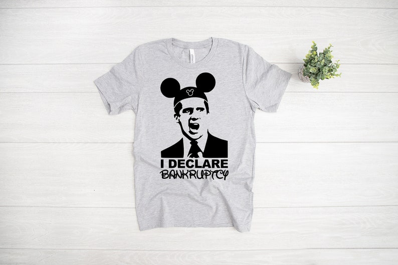 May include: A gray t-shirt with a black graphic of a man wearing Mickey Mouse ears and the text "I DECLARE BANKRUPTCY".
