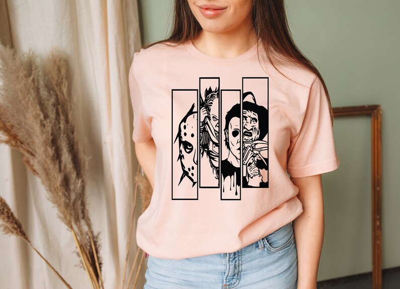 May include: A pink t-shirt with a black graphic of four horror movie characters. The characters are Jason Voorhees, Michael Myers, Freddy Krueger, and Leatherface.