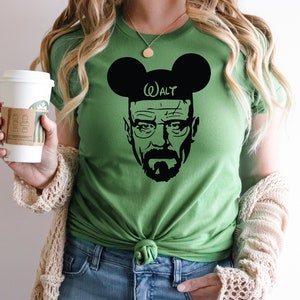 May include: Green t-shirt with a black silhouette of Walter White from Breaking Bad wearing Mickey Mouse ears with the text "Walt" on the headband.