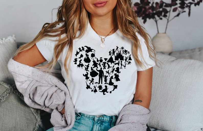 May include: A white t-shirt featuring a black silhouette of Mickey Mouse's head formed from various Disney characters.