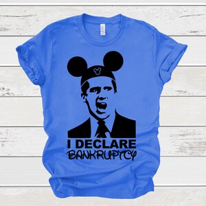 May include: A blue t-shirt with a black silhouette of a man wearing Mickey Mouse ears. The text "I DECLARE BANKRUPTCY" is printed on the shirt.