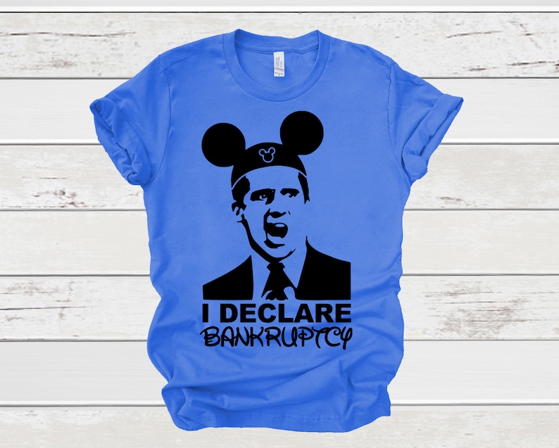 May include: A blue t-shirt with a black silhouette of a man wearing Mickey Mouse ears. The text "I DECLARE BANKRUPTCY" is printed on the shirt.