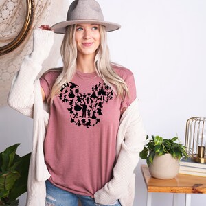 May include: A mauve t-shirt featuring a black silhouette of Mickey Mouse's head formed from various Disney characters and icons.