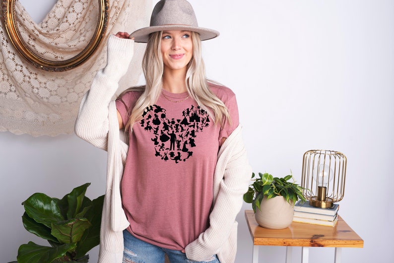 May include: A mauve t-shirt featuring a black silhouette of Mickey Mouse's head formed from various Disney characters and icons.