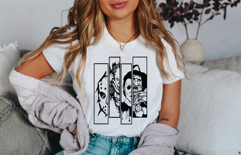 May include: White t-shirt with a black and white graphic print of four horror movie characters. The characters are Jason Voorhees, Freddy Krueger, Michael Myers, and Leatherface.