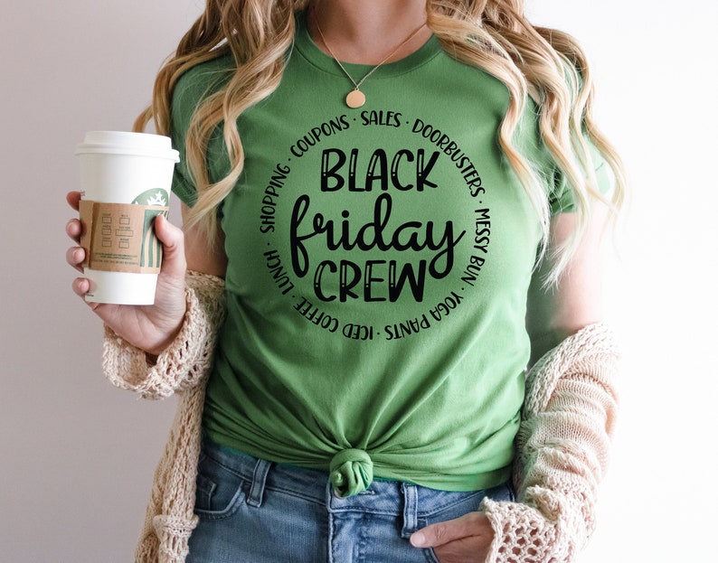 May include: A green t-shirt with a black circle graphic that says "Black Friday Crew" with a list of activities around the circle, including "iced coffee", "yoga pants", "messy bun", and "doorbusters".