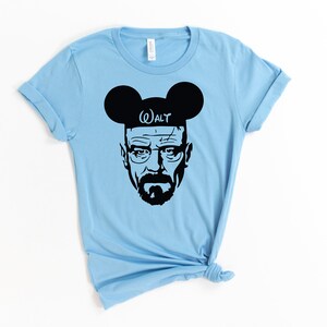 May include: Light blue t-shirt with a black silhouette of Walter White from Breaking Bad wearing Mickey Mouse ears with the word "WALT" on the headband.