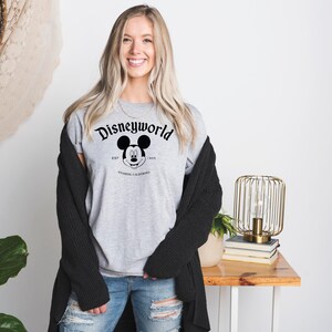 K&ouml;nnte beinhalten: Ein graues T-Shirt mit einem schwarz-wei&szlig;en Motiv von Mickey Mouse und dem Text "Disneyworld Est. 1971 Anaheim, Kalifornien".