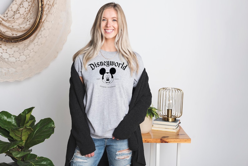 K&ouml;nnte beinhalten: Ein graues T-Shirt mit einem schwarz-wei&szlig;en Motiv von Mickey Mouse und dem Text "Disneyworld Est. 1971 Anaheim, Kalifornien".