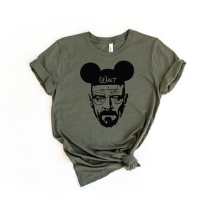 May include: A green t-shirt with a black silhouette of Walter White from the TV show Breaking Bad wearing Mickey Mouse ears with the text "WALT" on the ears.
