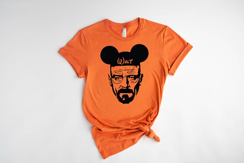 May include: Orange t-shirt with a black silhouette of Walter White from Breaking Bad wearing Mickey Mouse ears with the text "(W)ALT" on the headband.