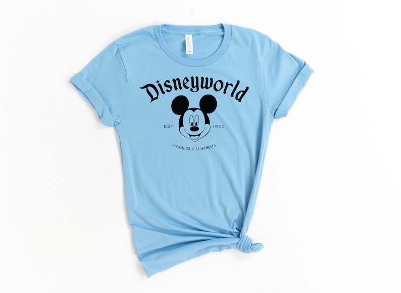 K&ouml;nnte beinhalten: Hellblaues T-Shirt mit einem schwarzen Mickey Mouse Kopf und dem Text "Disneyworld Est. 1955 Anaheim, Kalifornien".
