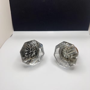 Puede incluir: Dos pomos de puerta de vidrio transparente con un diseño facetado. Los pomos tienen un acabado plateado y están en buen estado.