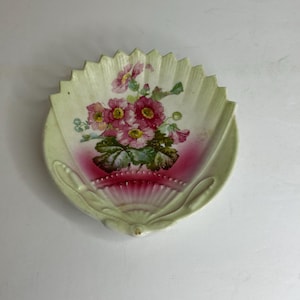 May include: A vintage porcelain dish shaped like a seashell with a pink and green floral design.
