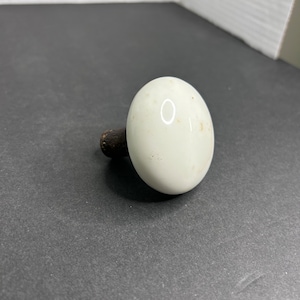 May include: White ceramic bottle stopper with a rounded top and a brown wooden base.