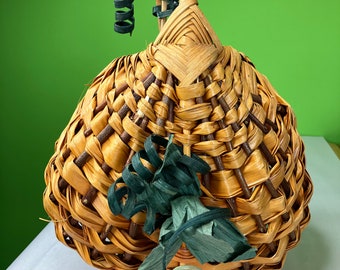 May include: A woven wicker basket shaped like a pumpkin with a handle and green ribbon accents.