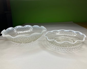 Puede incluir: Dos cuencos de vidrio transparente con un acabado blanco iridiscente. Los cuencos tienen un borde festoneado y un patrón texturizado de puntos en relieve.