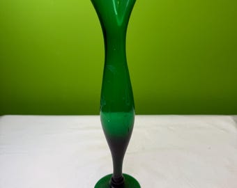 May include: A tall, elegant green glass vase with a flared top and a slender, elongated body. The vase has a dark green base and a lighter green upper portion. The vase is approximately 10 inches tall.