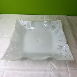 May include: White frosted glass ceiling light fixture with a square shape and a scalloped edge. The glass has a floral pattern etched into it.