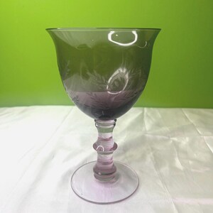 May include: A clear glass goblet with an etched design and a purple tinted stem and base.
