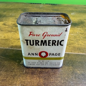 Può includere: Un barattolo per spezie rettangolare in metallo vintage con sfondo bianco e coperchio arrugginito. La parte anteriore presenta testo rosso e nero che recita Pure Ground TURMERIC, ANN PAGE e THE GREAT ATLANTIC AND PACIFIC TEA COMPANY, NEW YORK, N. Y., DISTRIBUTOR.