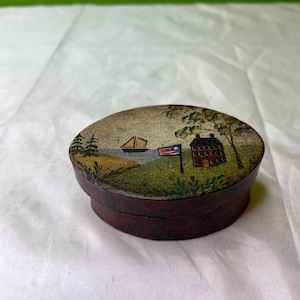 Caja de baratijas vintage de cartón o papel pintada a mano con bandera estadounidense, velero, casa de ladrillo y árboles.