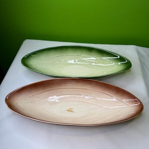 Puede incluir: Dos fuentes ovaladas. Una es verde, desvaneciéndose a un verde más claro en el centro. La otra es marrón, desvaneciéndose a un color crema en el centro. Ambas tienen un diseño de hojas.