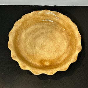 Pode incluir: Uma forma de torta de cerâmica marrom com borda ondulada.