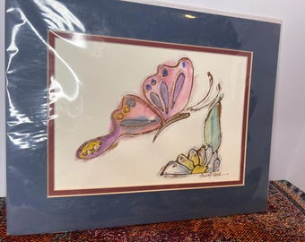 May include: A framed watercolor painting of a pink butterfly with purple and yellow accents, landing on a flower with green leaves. The painting is signed "Sandy York" in the bottom right corner.