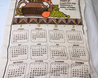 May include: A vintage linen calendar towel featuring a brown pitcher with orange flowers, a pear, and grapes. The towel displays a calendar for the year with months and dates, and the text "For today well lived makes yesterday a dream of happiness and tomorrow a vision of hope."