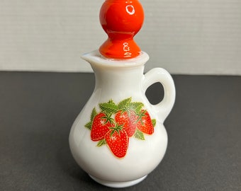 Puede incluir: Jarra de cerámica blanca con un tapón rojo en forma de bola y un diseño de fresas.