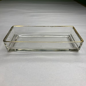 Peut inclure: Un plat rectangulaire en verre transparent avec un bord doré.