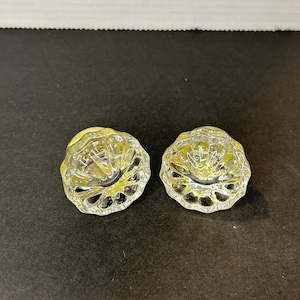 May include: Two clear glass bottle stoppers with a decorative, faceted design.