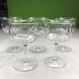 Pode incluir: Conjunto de cinco copos de vinho de vidro transparente com haste e design texturizado com bolhas.