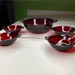 May include: Set of five red glass bowls with handles. The bowls are of varying sizes, with the largest bowl having two handles.