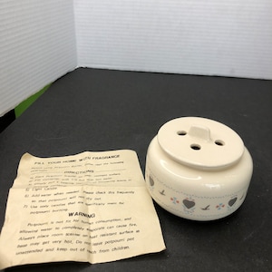 May include: White ceramic potpourri burner with a lid and three holes. The potpourri burner has a blue and red floral design with birds. The instructions on the packaging say "Fill your home with fragrance".