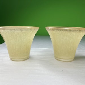 May include: Two clear, light yellow glass lampshades with a textured, vertical, striated pattern.