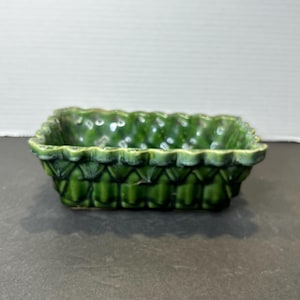 Może przedstawiać: Zielona ceramiczna doniczka z fakturowanym, plecionym wzorem. Doniczka ma prostokątny kształt z falistym brzegiem.
