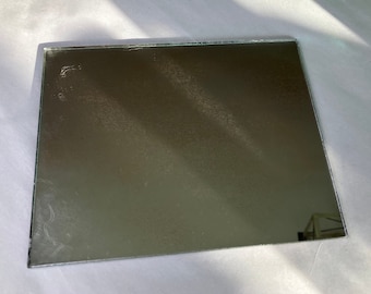 May include: A rectangular mirror with a silver frame. The mirror is slightly cloudy and has a few scratches on the surface.