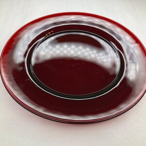 May include: A deep red glass dinner plate with a raised rim.